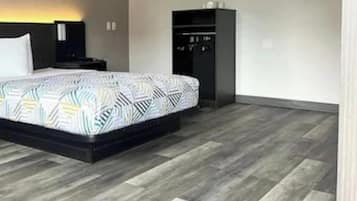 Una habitación de hotel moderna con una cama grande, un armario y una mesita de noche.