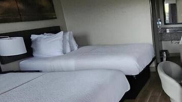 A hotel room with two beds, a bathroom, and a painting on the wall.