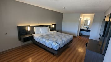 Una habitación de hotel moderna con una cama grande, mesitas de noche, una cómoda, un escritorio integrado, un espejo y un armario.