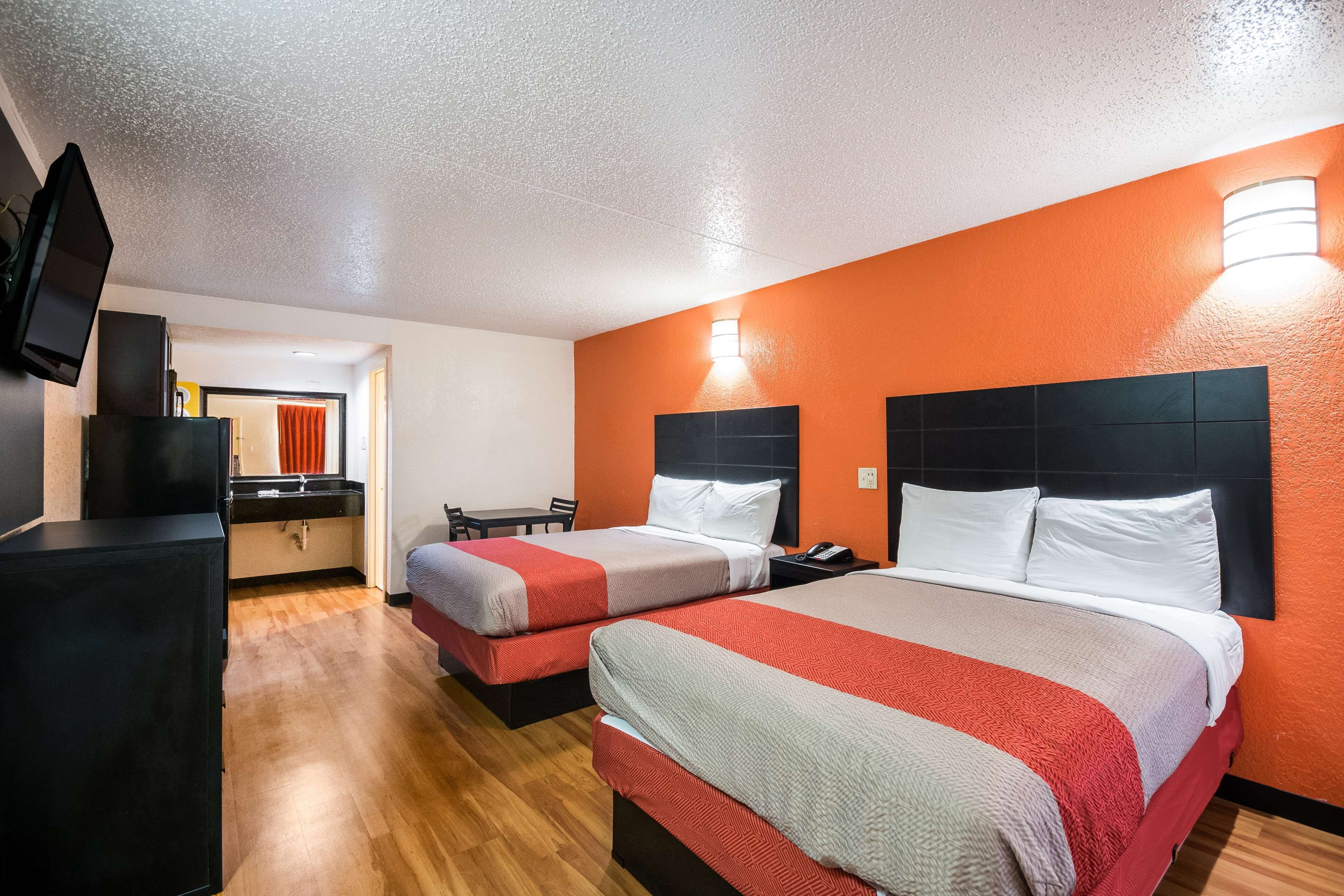 Een hotelkamer met twee bedden, een televisie, een bureau en een badkamer in de achtergrond.