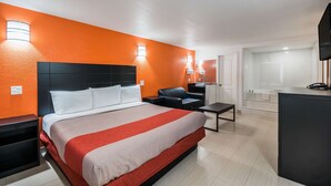 A hotel room with a large bed, a desk, a chair, and a TV. - Motel 6 Houston, TX - Brookhollow (Houston)