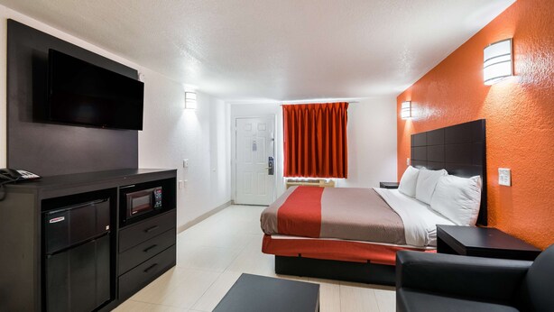 A hotel room with a bed, a desk with a flat-screen TV, a microwave, and a refrigerator. - Motel 6 Houston, TX - Brookhollow (Houston)