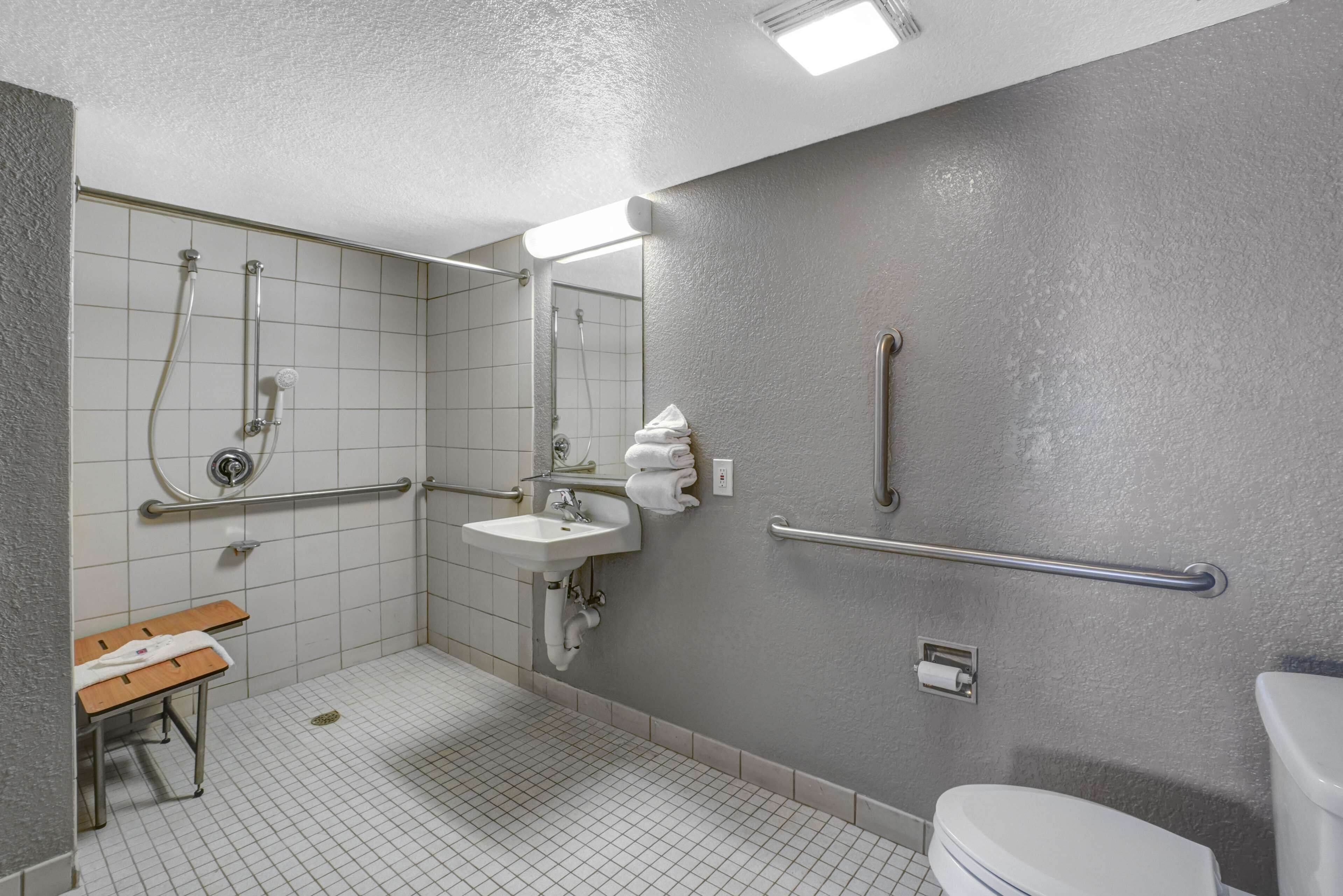 Un baño con lavamanos, espejo, ducha e inodoro.