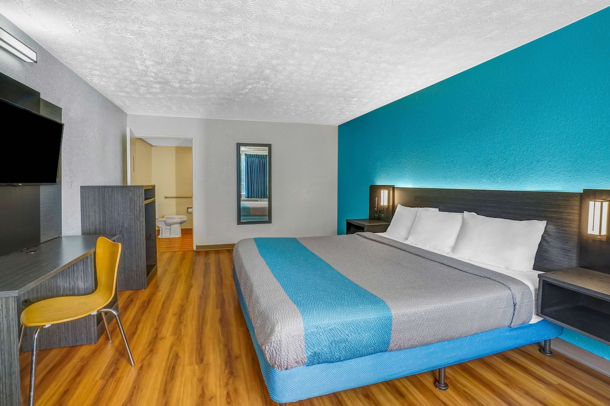 A modern hotel room with a large bed, a desk, and a chair.