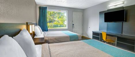 A hotel room with two beds, a television, a desk, and a window with curtains.