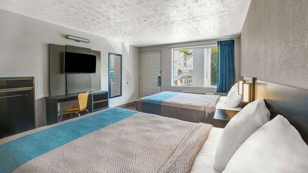 A hotel room with two beds, a TV, a desk, and a window with curtains. - Motel 6 Lexington I-75 Hamburg (Lexington)