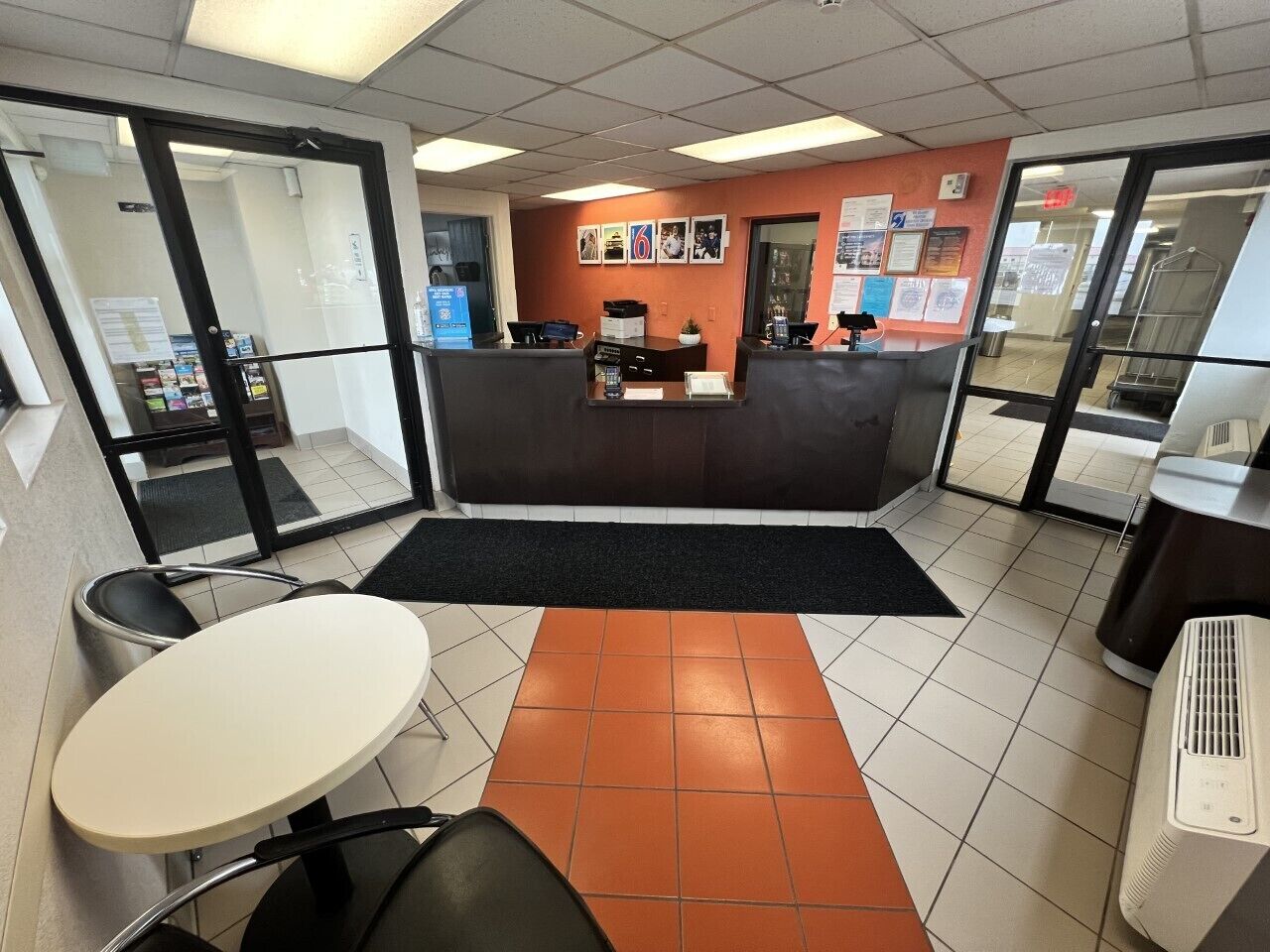 A reception area with a counter, chairs, a table, and a tiled floor.