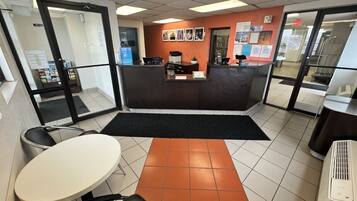 A reception area with a counter, chairs, a table, and a tiled floor.