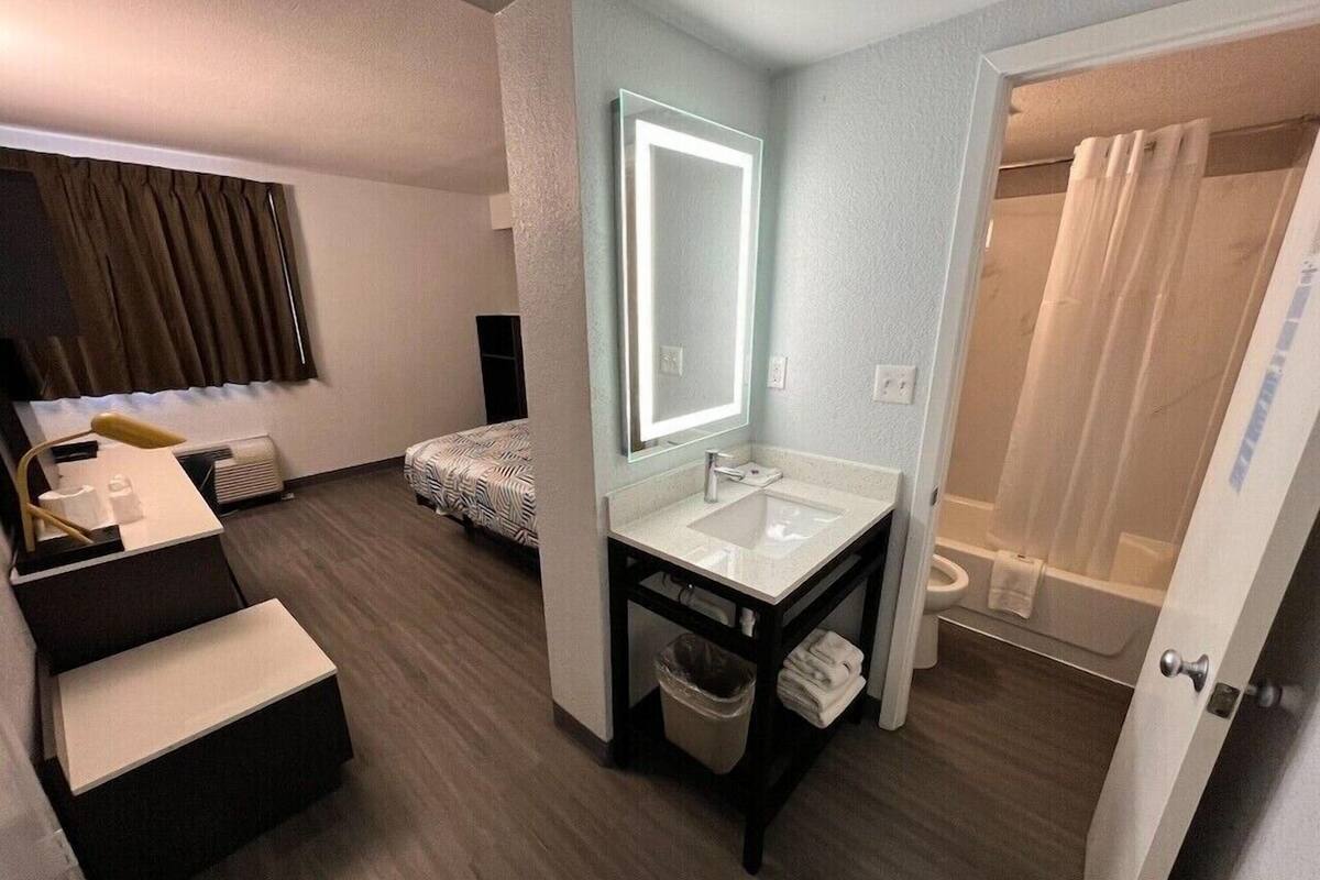 A hotel bathroom with a large mirror, a sink, a toilet, and a shower area.