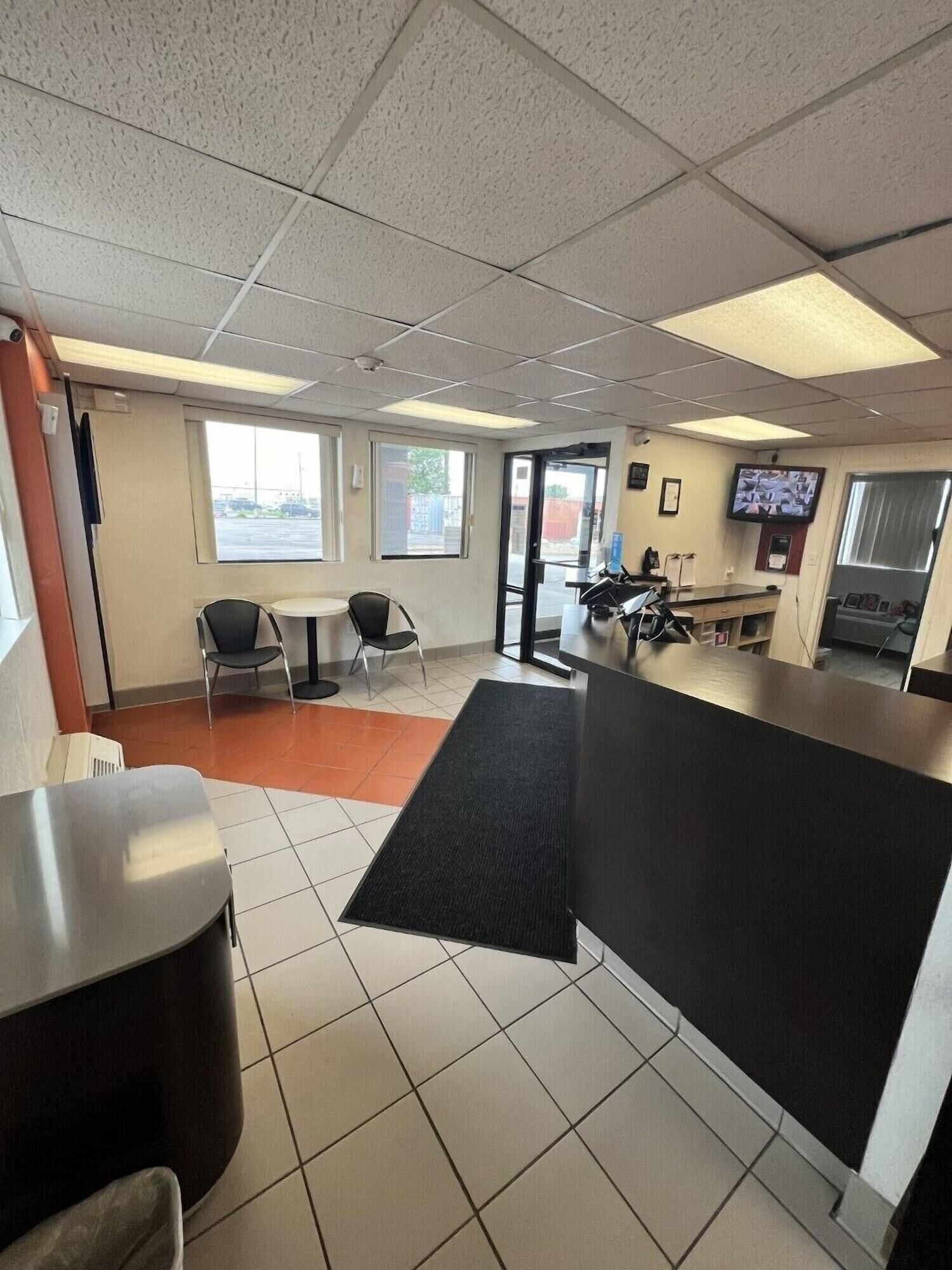 A spacious lobby with a reception desk, seating area, and a television screen.