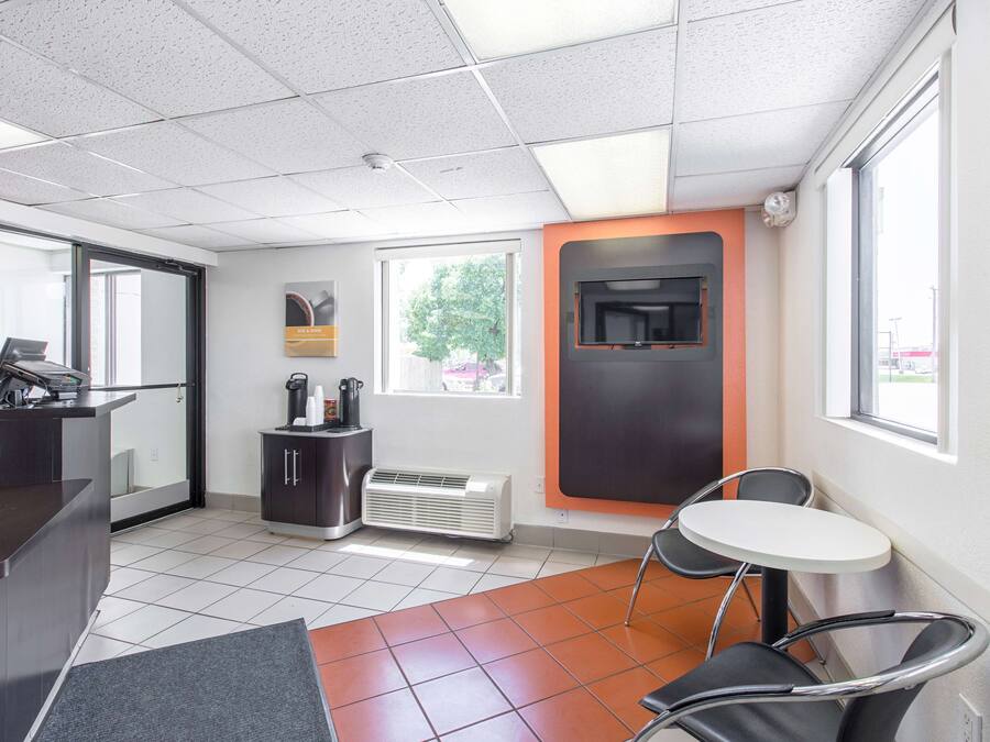 A modern office space with a reception desk, a small seating area, and a large window providing natural light.