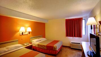 A hotel room with two beds, a desk, a chair, a television, a lamp, and a window with curtains.