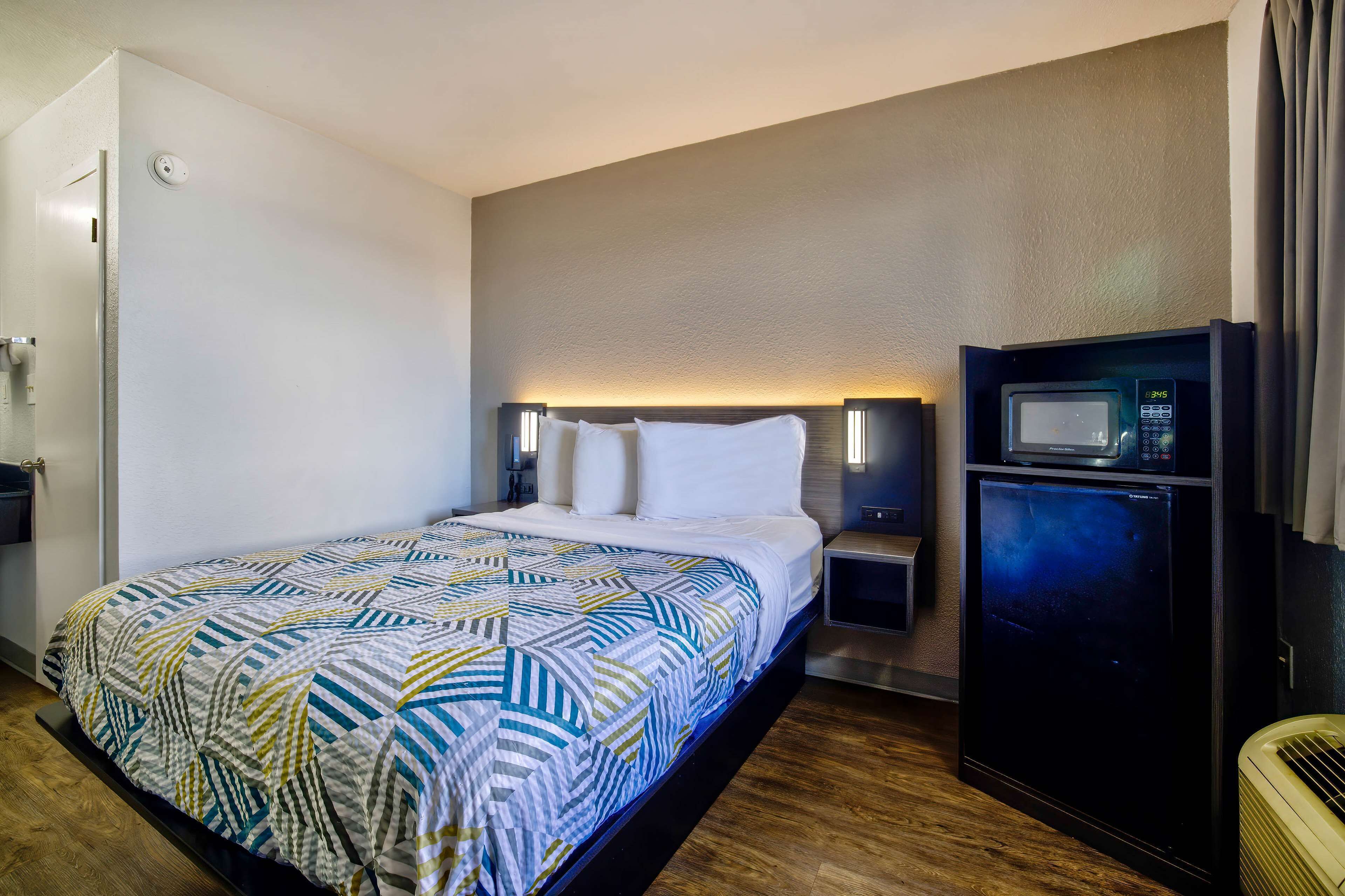 Ein Hotelzimmer mit einem Bett, einer Mikrowelle, einem kleinen Kühlschrank und einem Nachttisch.