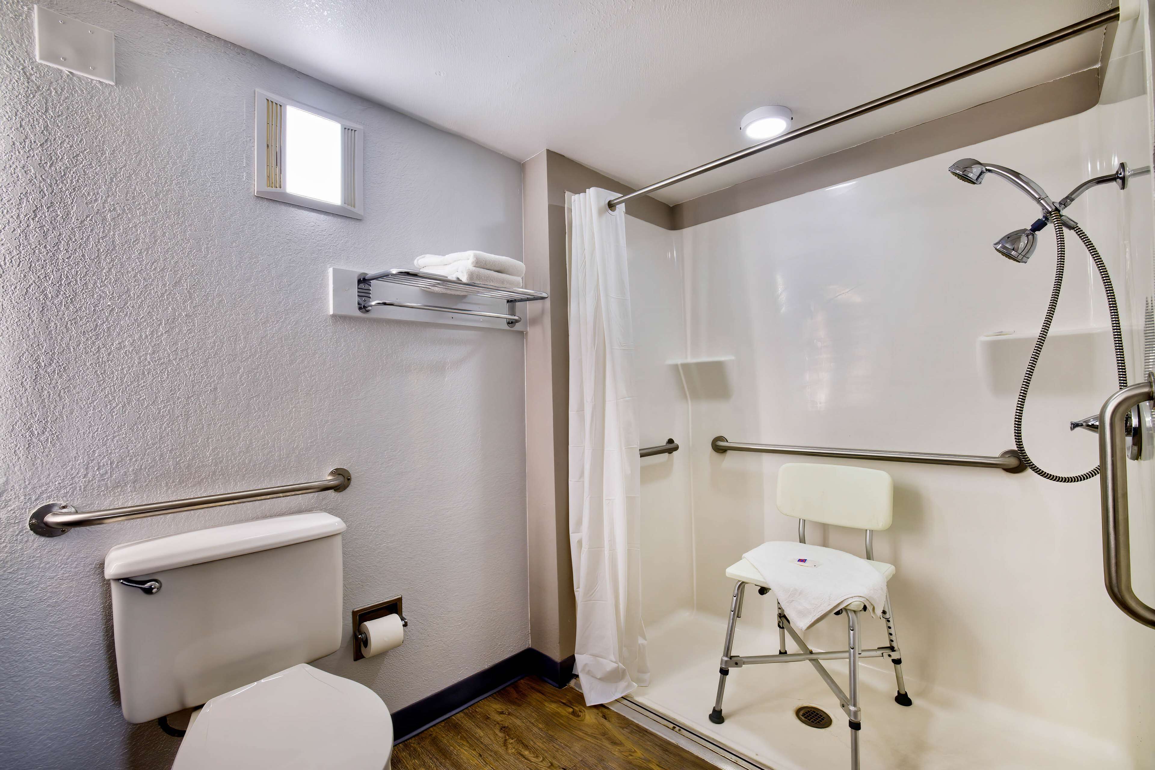 Une salle de bain équipée d’une douche, de toilettes et de barres d’appui.