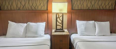 A hotel room with two beds, a nightstand with a lamp, and a decorative wall panel.
