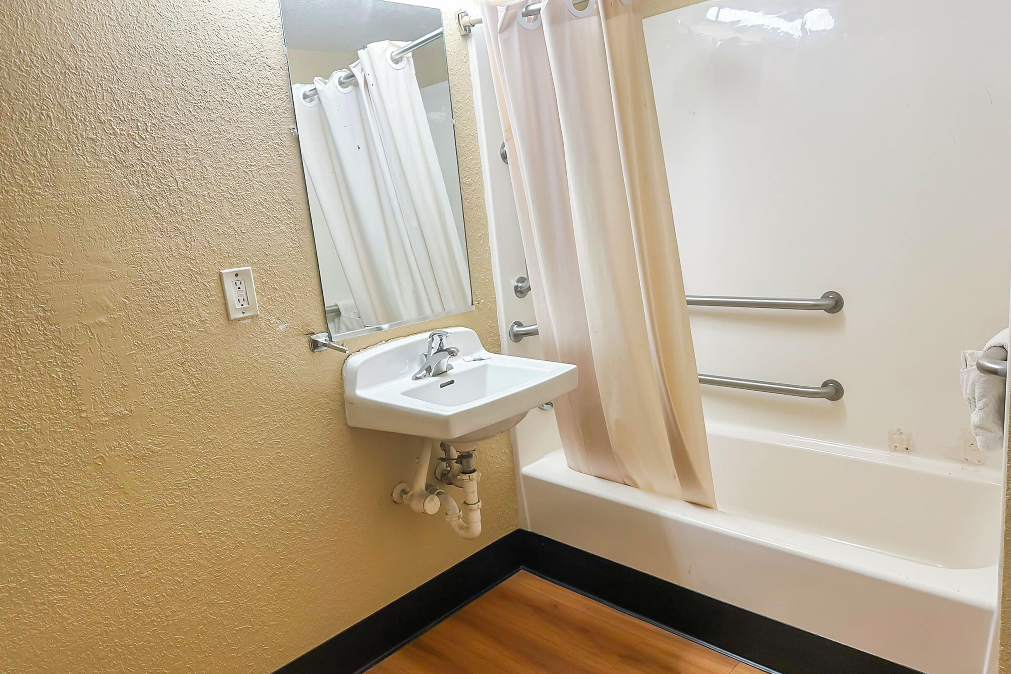 A bathroom with a white sink, mirror, and bathtub.