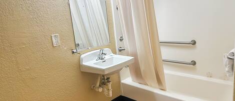 A bathroom with a white sink, mirror, and bathtub.