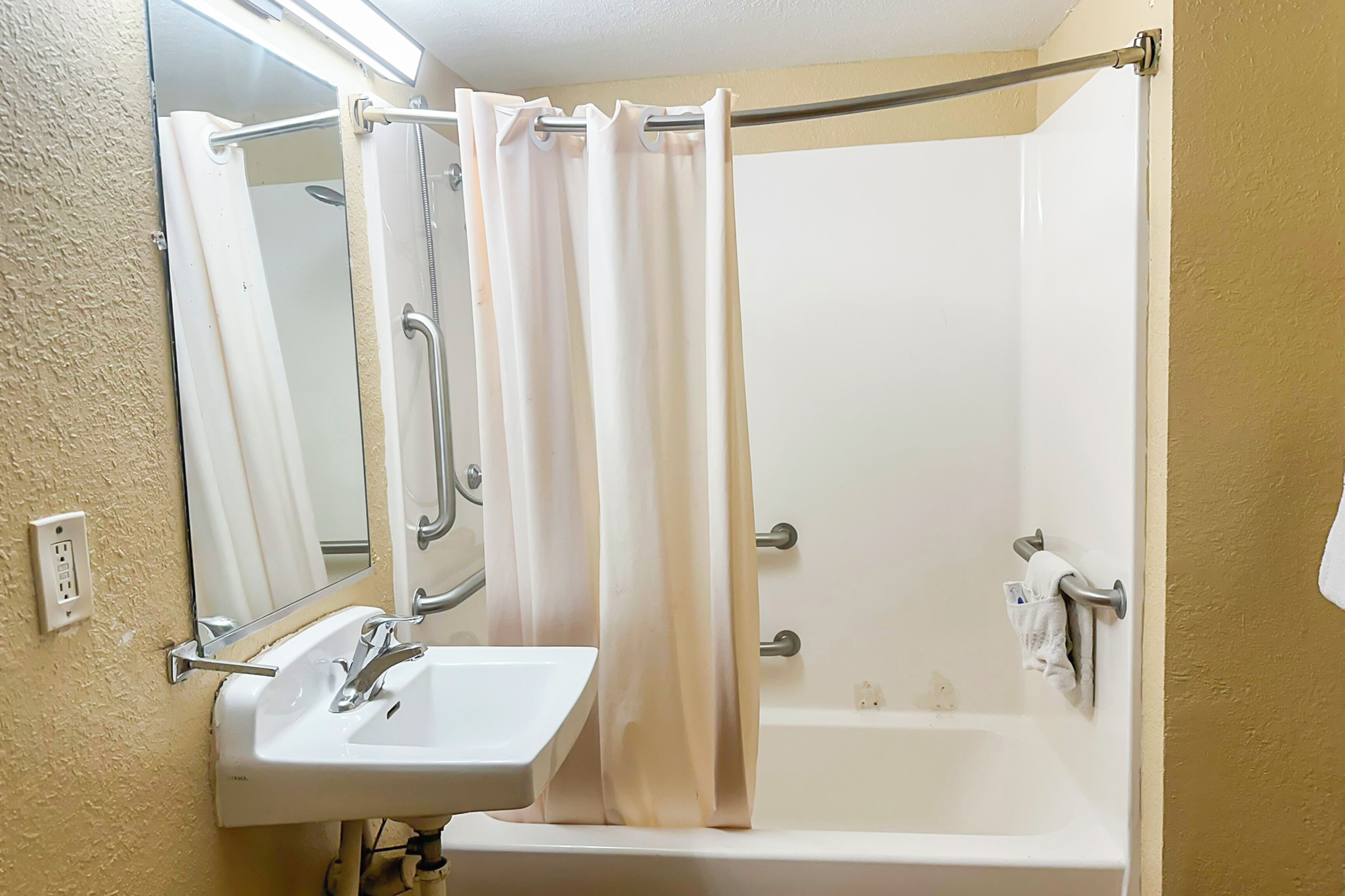 A bathroom with a white sink, mirror, and bathtub.