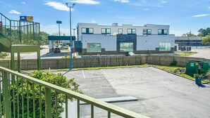 Ein modernes Gebäude mit flachem Dach, großen Fenstern und einem Parkplatz davor.