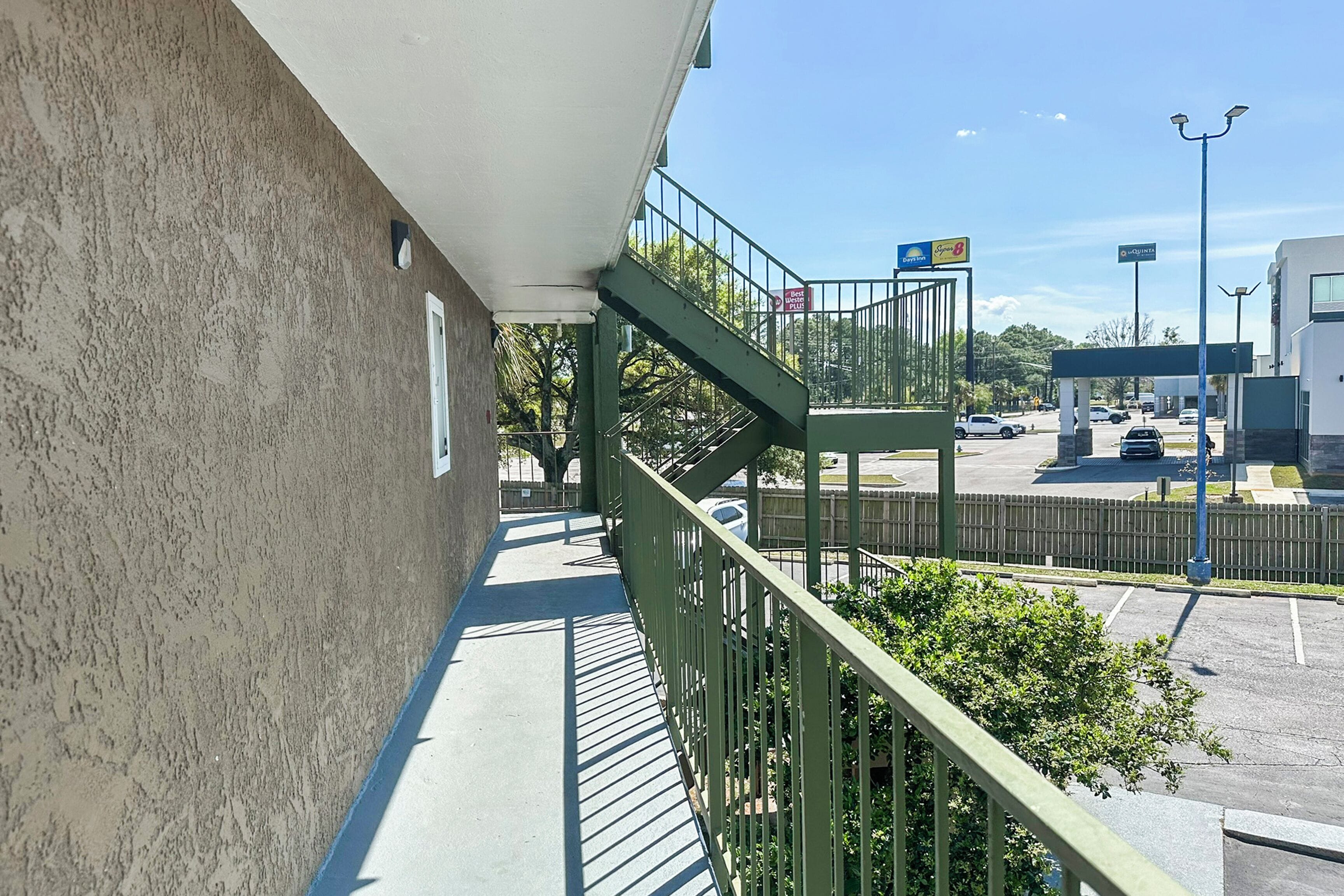 Un edificio con una escalera verde que conduce a un área de estacionamiento.