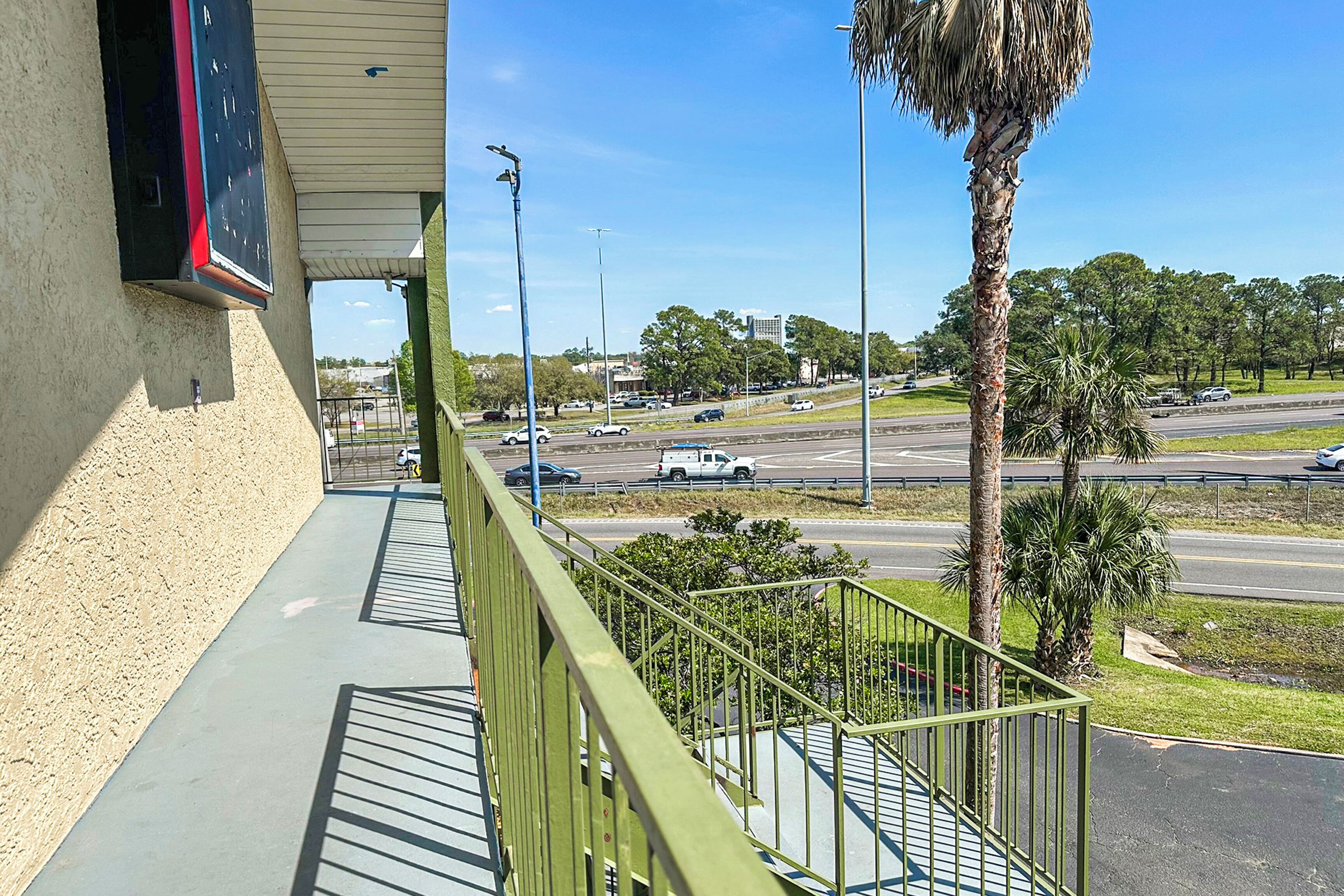A balcony with a view of a busy road and palm trees.