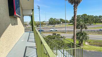 A balcony with a view of a busy road and palm trees.