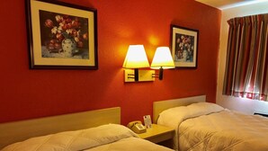 A hotel room with two beds, a nightstand with a telephone, and wall-mounted lamps. - QC Stay Inn (Moline)