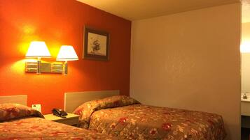 Two beds with floral-patterned bedding, a warm accent wall, and a framed artwork adorn this cozy retreat.