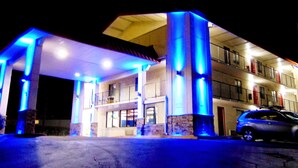 A hotel with a covered entrance, multiple floors, and a car parked outside. - Somatel Nashville Airport Hotel (Nashville)