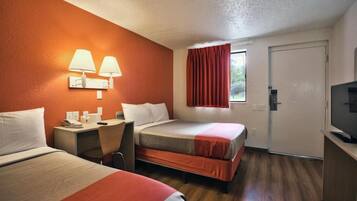 A hotel room with two beds, a desk with a telephone, and a television.