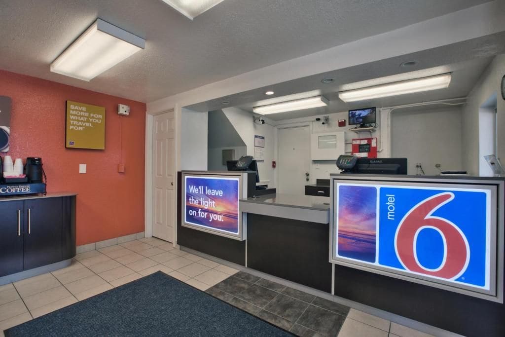A motel reception area with a coffee station, a sign indicating the motel number, and a message about the lights being left on.