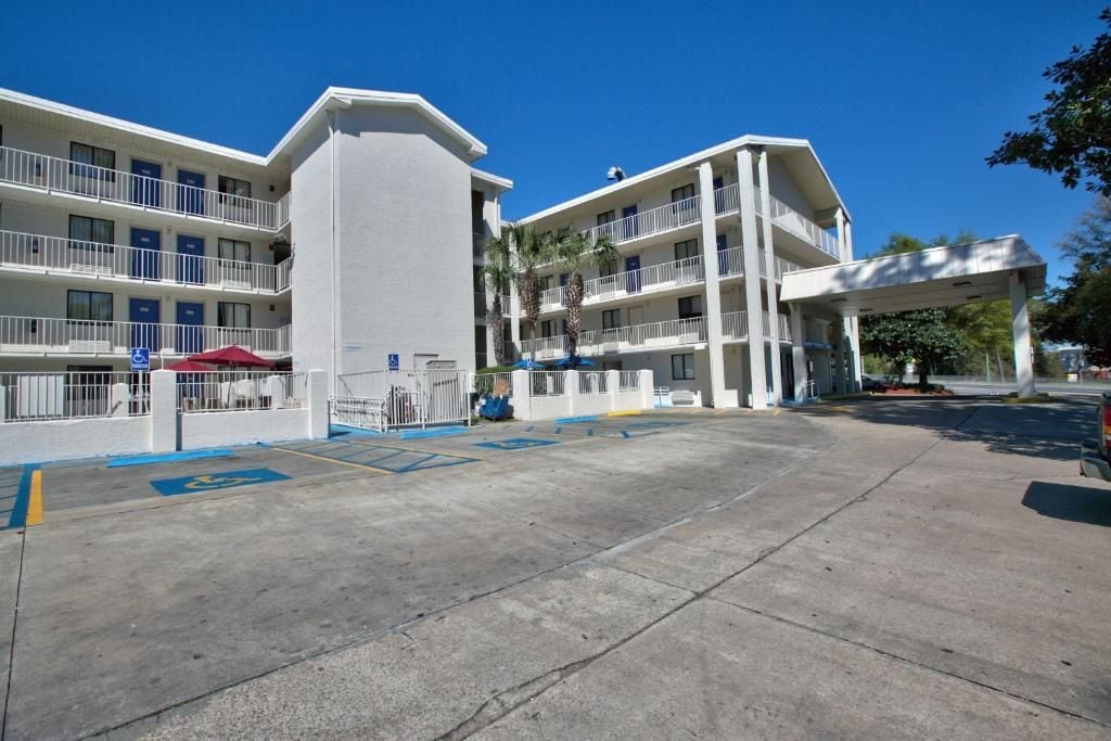 Un hotel de varios pisos con un patio central, asientos al aire libre y una zona cubierta.