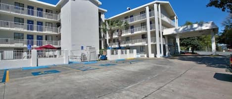 Un hotel de varios pisos con un patio central, asientos al aire libre y una zona cubierta.