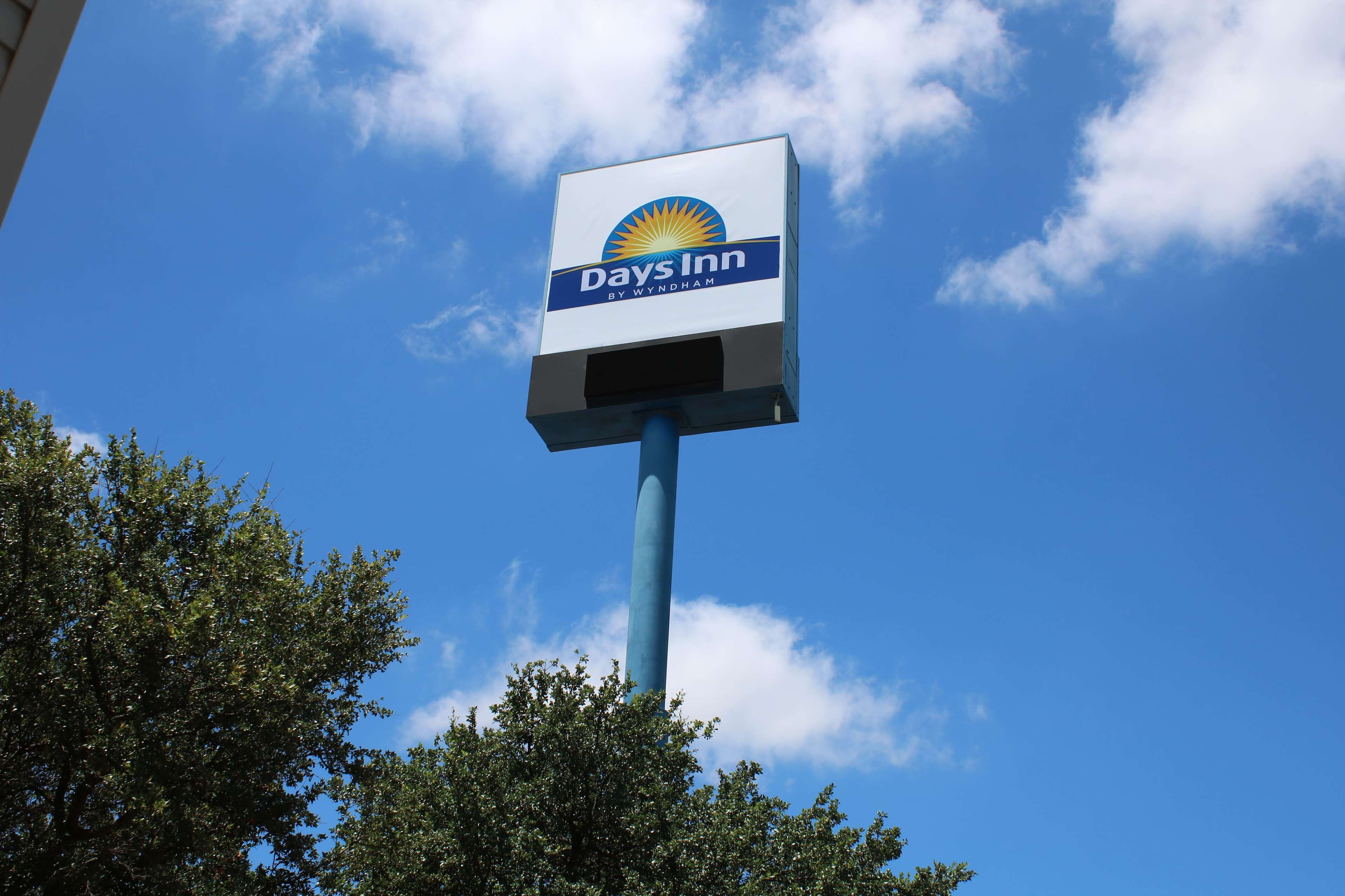 A Days Inn sign against a clear blue sky with some clouds.
