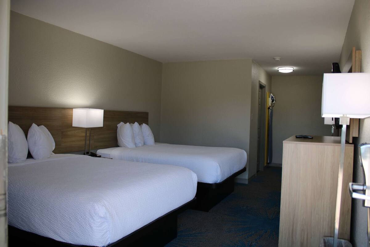 Une chambre d’hôtel avec deux lits, un bureau et une lampe.