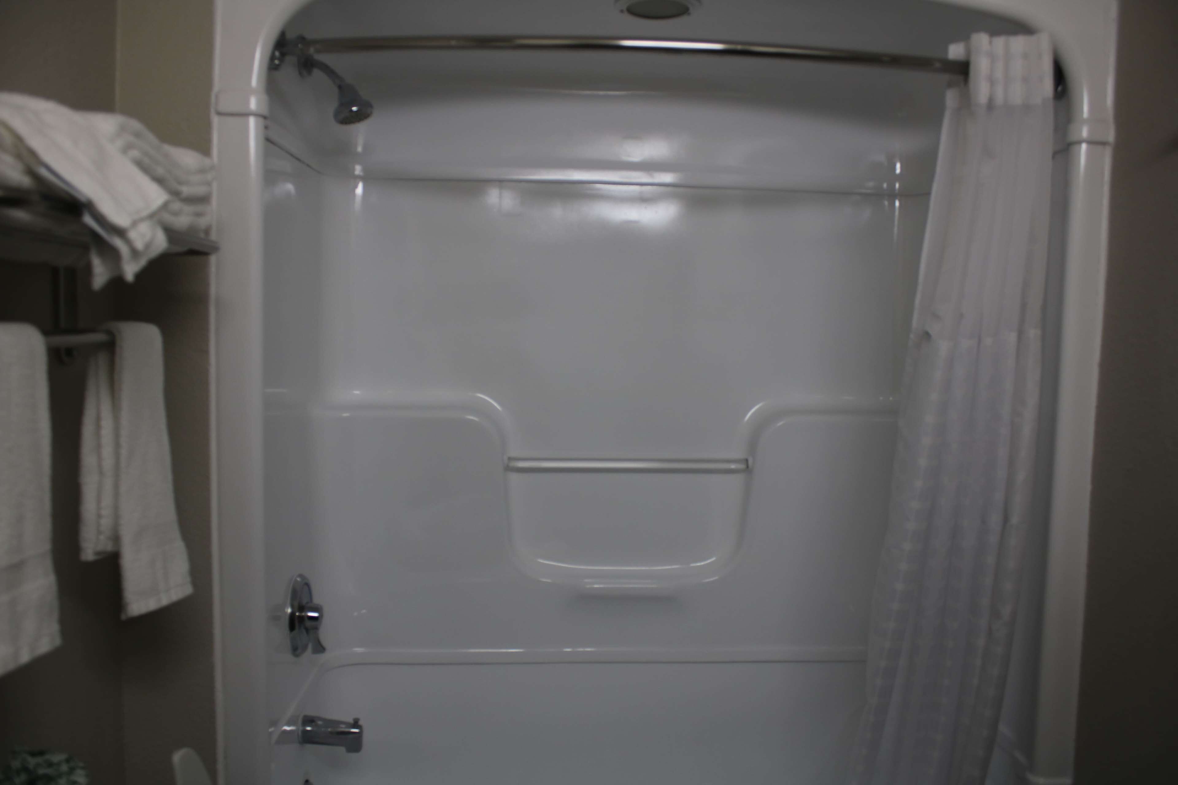 Ein Badezimmer mit Dusche, Handtuchhalter und Handtüchern sowie Toilette.