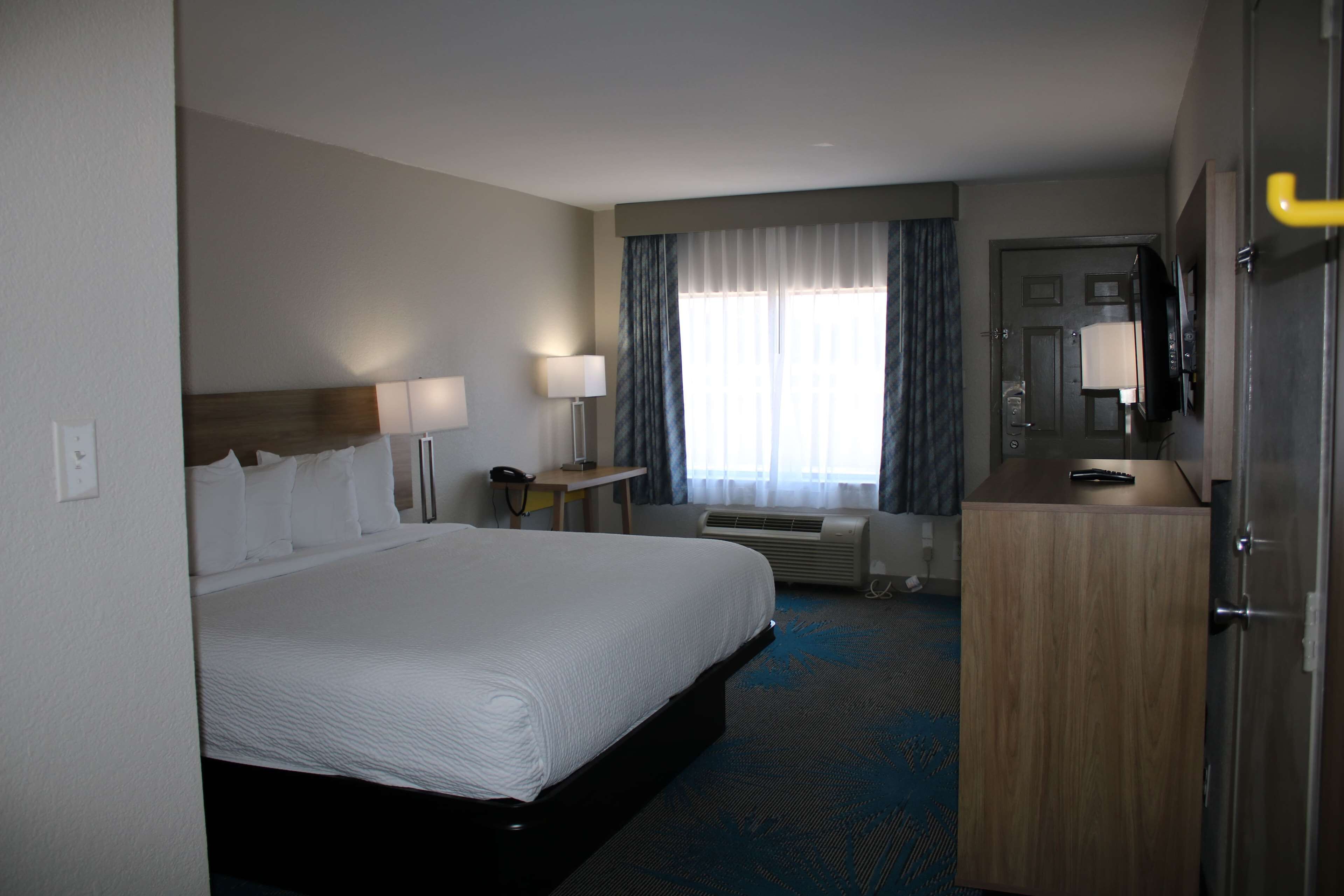 Une chambre d’hôtel avec un grand lit, des lampes de chevet, un bureau avec un téléphone, une télévision et une armoire.