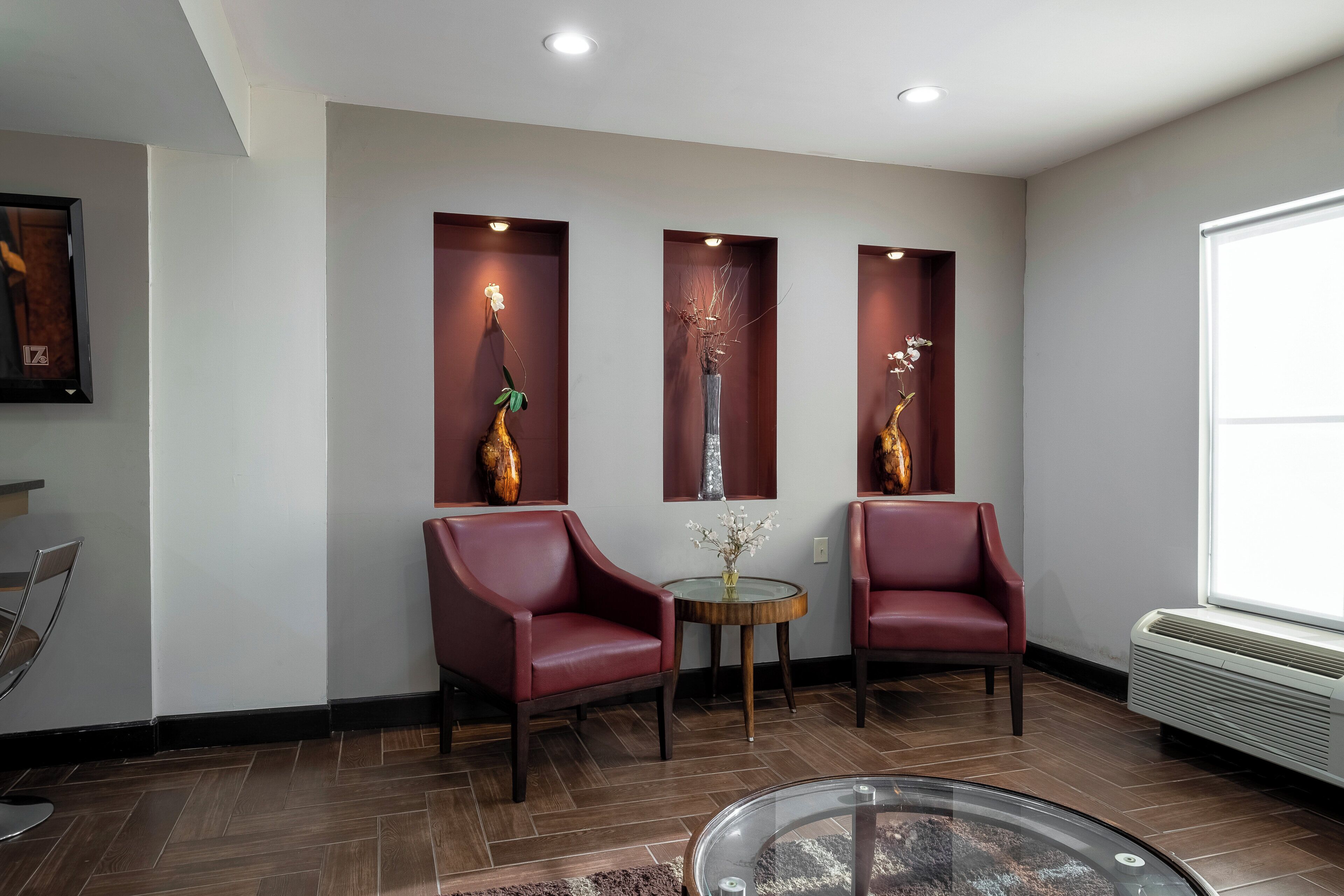 Un espace d’attente moderne avec deux fauteuils en cuir, une table en verre et des vases décoratifs.