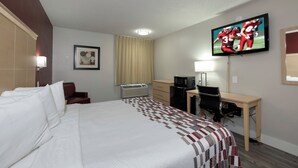 A hotel room with a large bed, a desk, a television, a heater, and a window with curtains. - Red Roof Inn Raleigh North-Crabtree Mall/Lenovo Center (Raleigh)