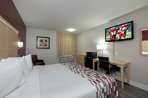 A hotel room with a large bed, a desk, a television, a heater, and a window with curtains. - Red Roof Inn Raleigh North-Crabtree Mall/Lenovo Center (Raleigh)