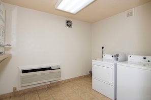 A laundry room with a wall-mounted heater, a vent, and stacked washing machines. - Red Roof Inn Raleigh North-Crabtree Mall/Lenovo Center (Raleigh)