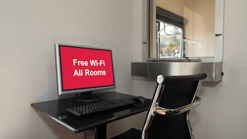 A workspace with a computer, keyboard, and chair, and a sign indicating free Wi-Fi availability.
