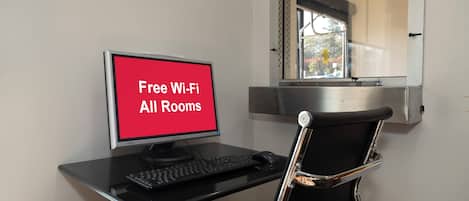 A workspace with a computer, keyboard, and chair, and a sign indicating free Wi-Fi availability.