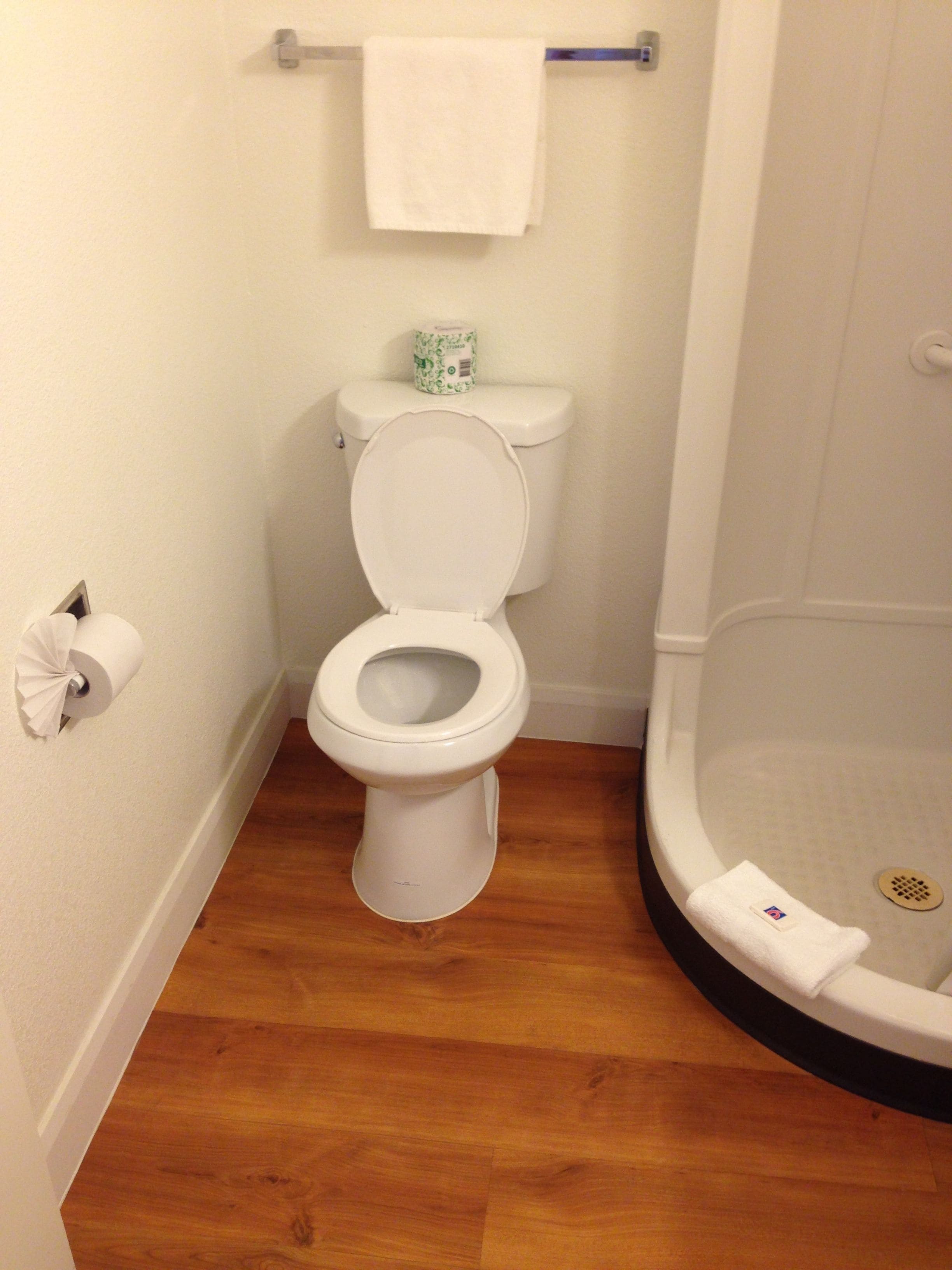 Casa de banho pequena com sanita, rolo de papel higiénico e zona de duche.