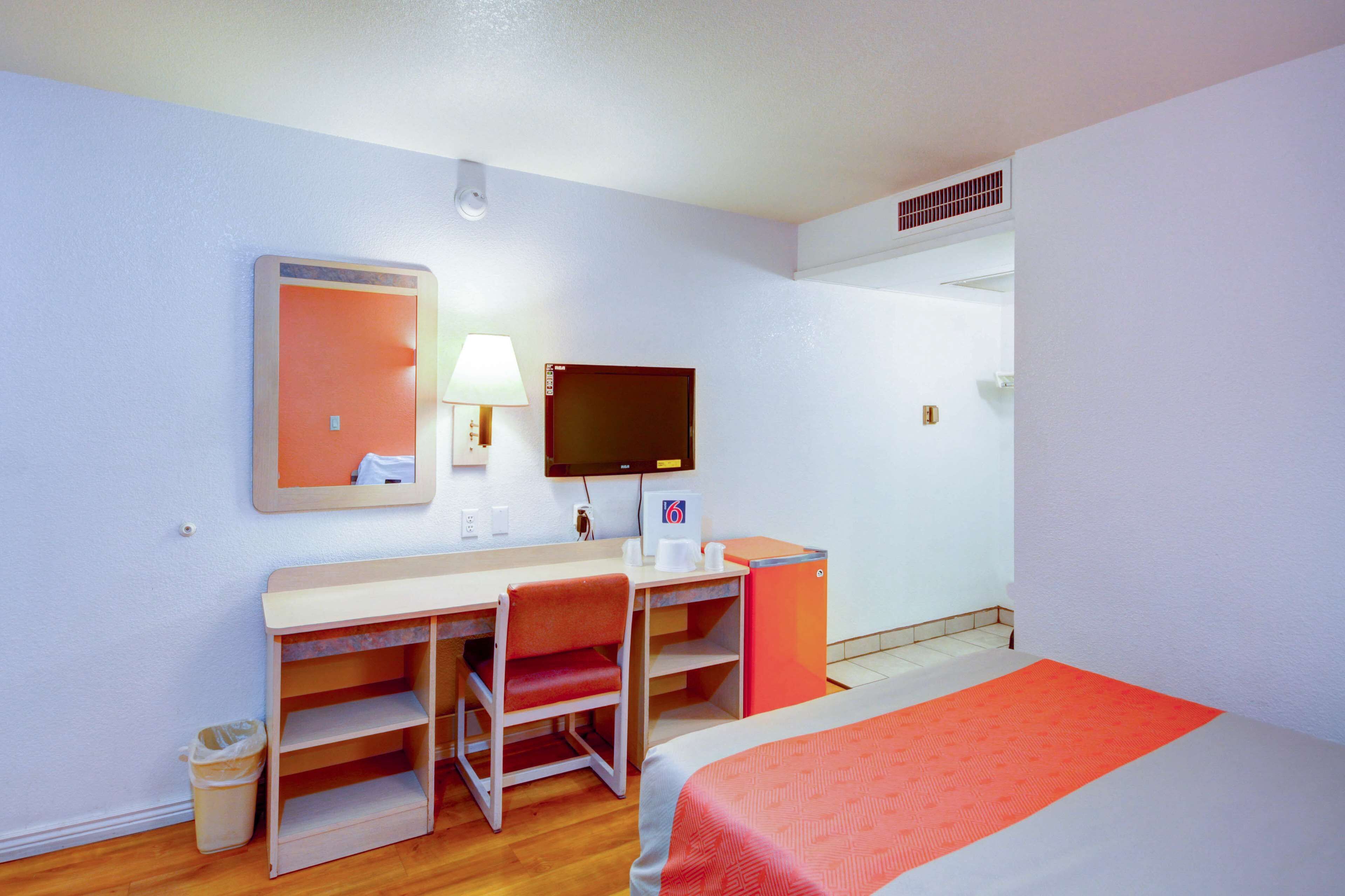 Ein Hotelzimmer mit Bett, Schreibtisch, Stuhl und Fernseher.