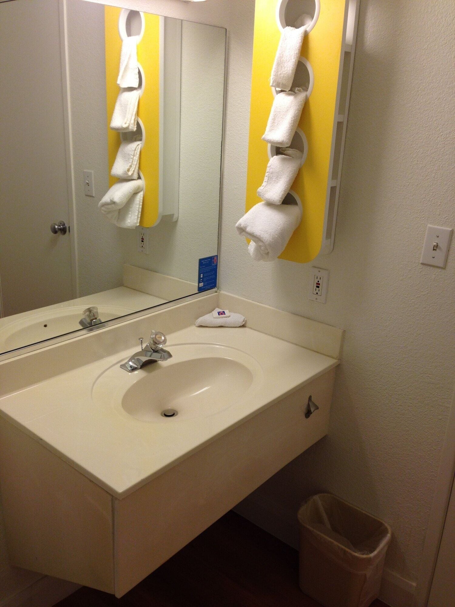 A bathroom with a white sink, a mirror, and a towel rack.