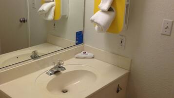 A bathroom with a white sink, a mirror, and a towel rack.