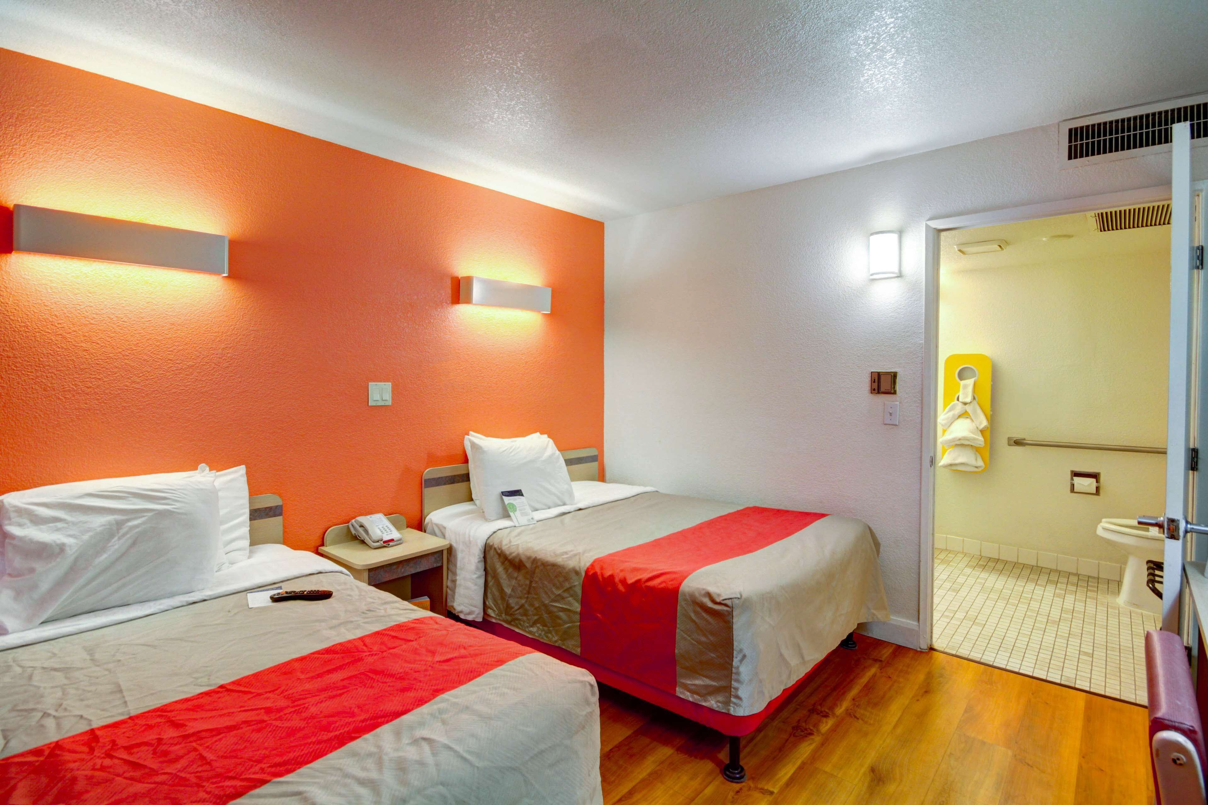 A hotel room with two beds, a bathroom, and a door leading to the hallway.