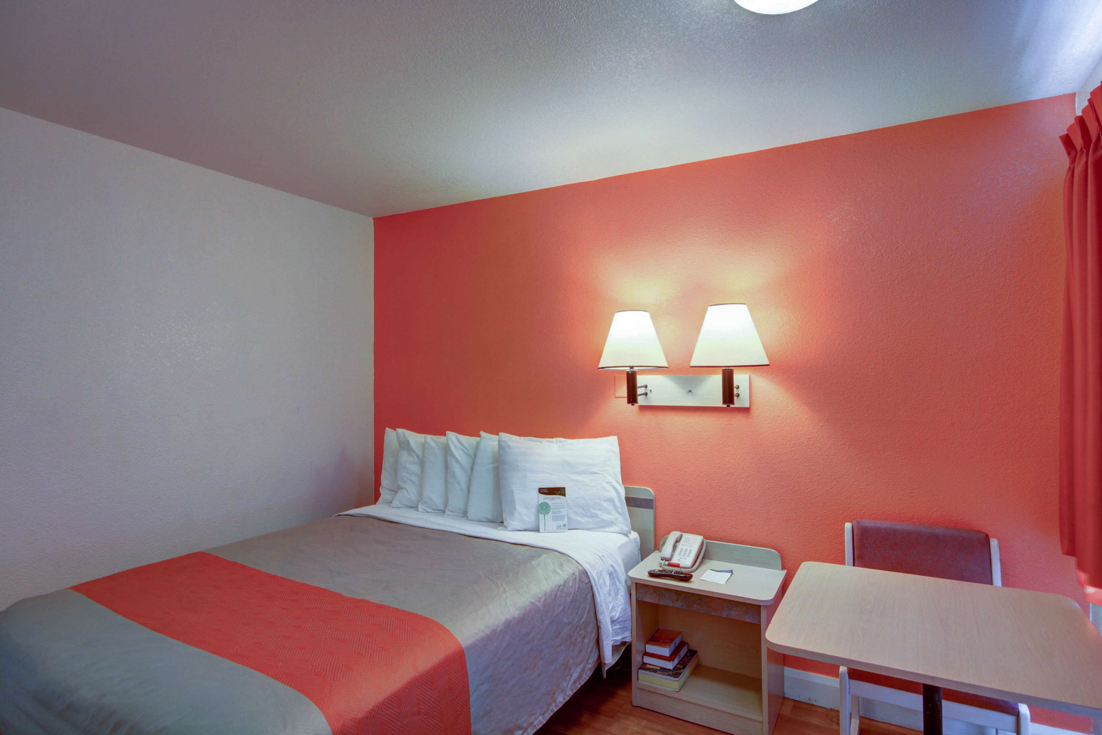 Une chambre d’hôtel avec un lit, une table de chevet avec une lampe, une chaise et une petite table.