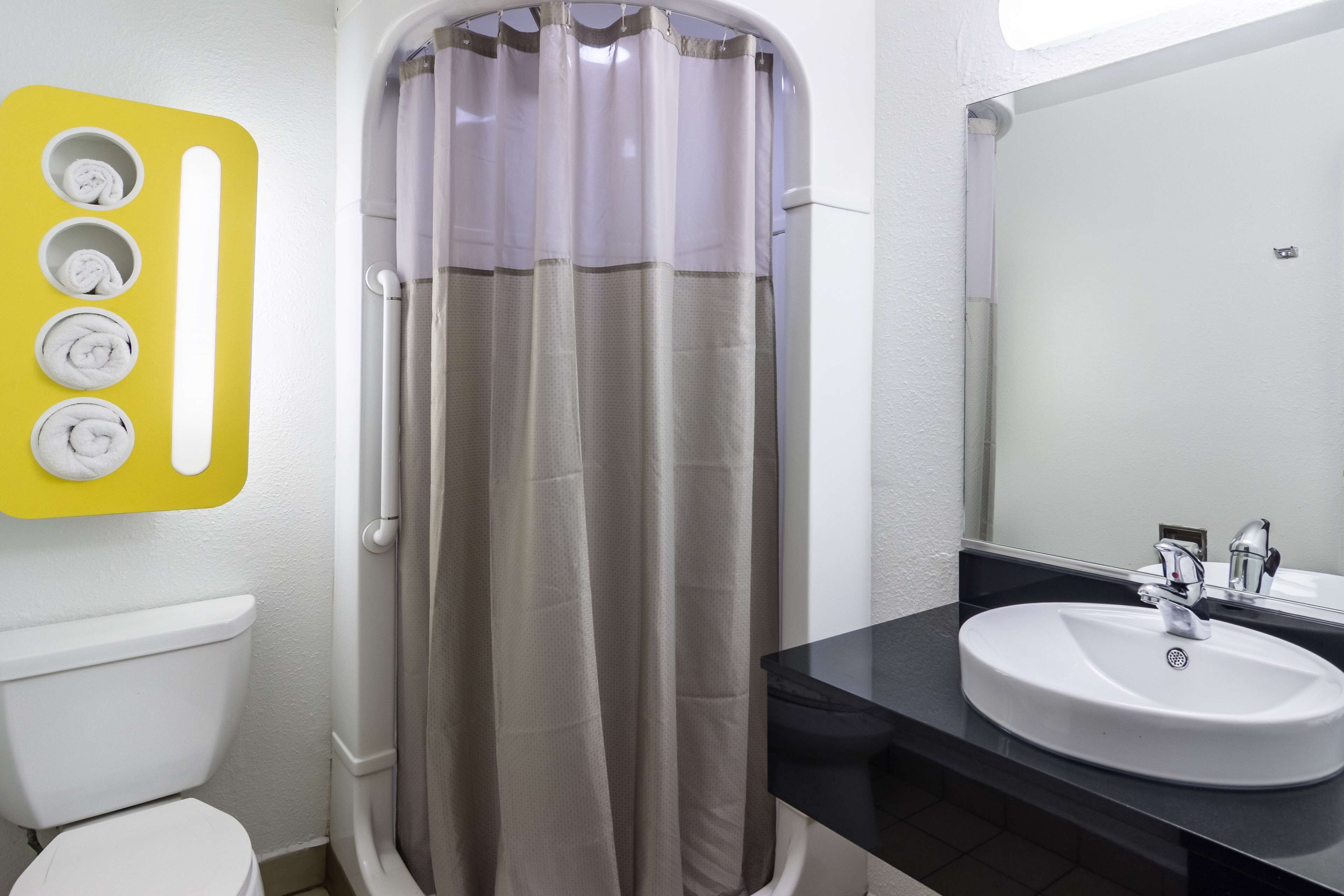 A bathroom with a shower curtain, a toilet, a sink, and a mirror.